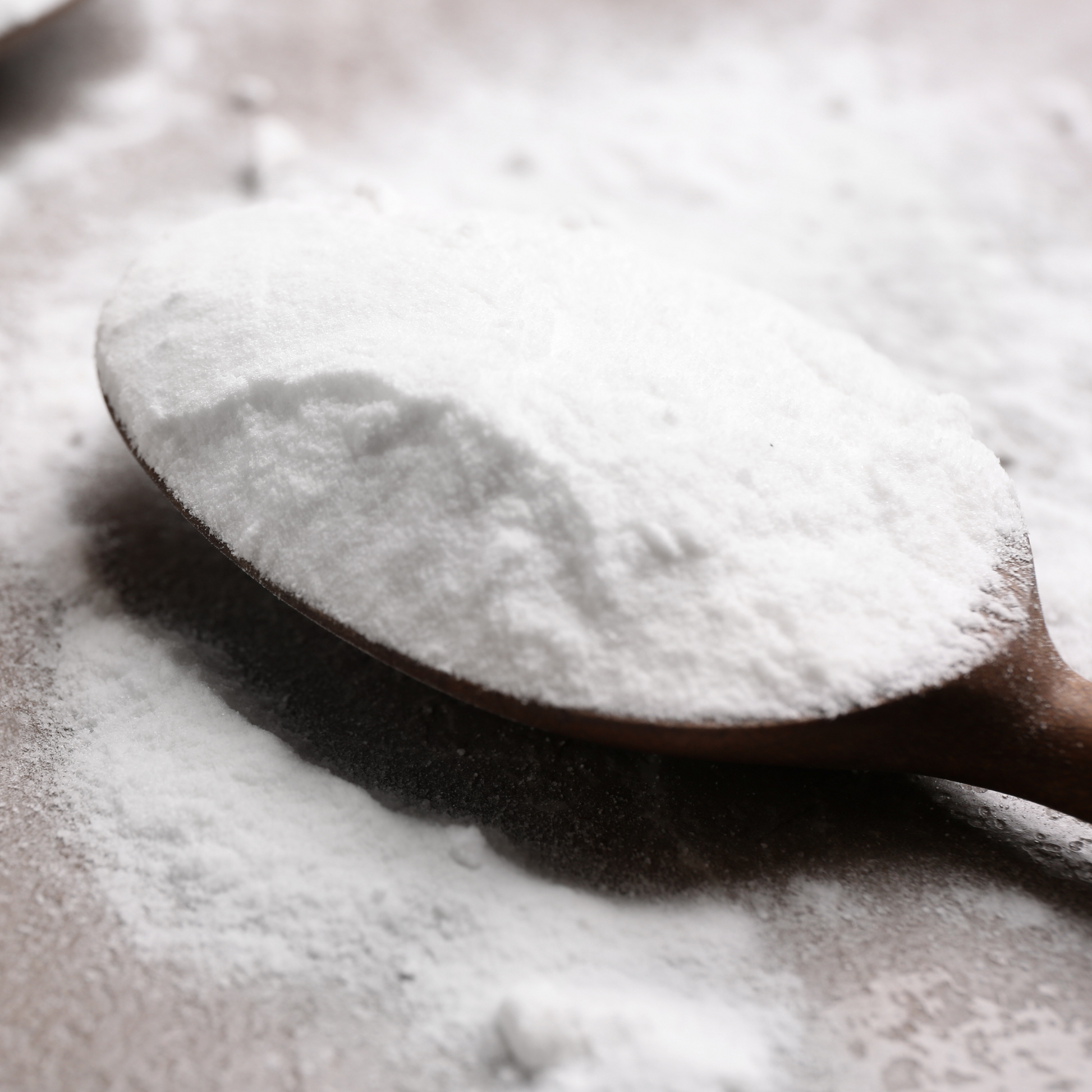 A wooden spoon with a scoop of Bicarb Soda/baking Soda (sodium bicarbonate)