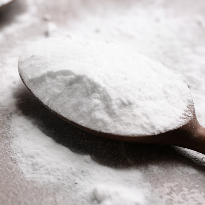 A wooden spoon with a scoop of Bicarb Soda/baking Soda (sodium bicarbonate)