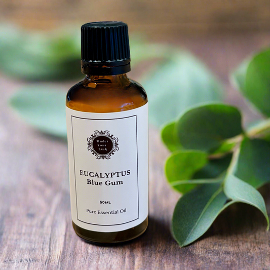 Amber glass essential oil bottle with white label with Under Your Sink logo and description Eucalyptus Blue Gum essential oil. Has blurred images of eucalyptus in background
