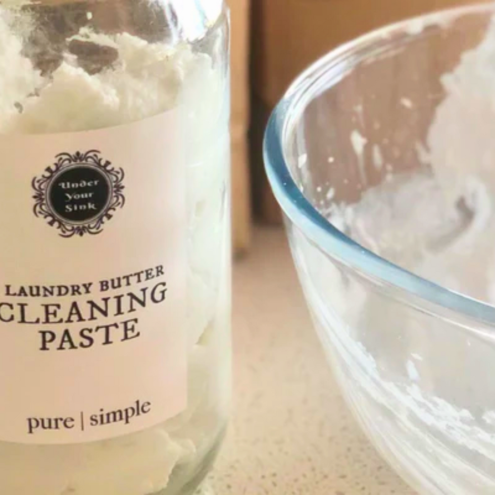 A clear bowl with a handmade white cleaning paste that looks and feels like whipped buttercream. Its next to a clear jar for storing it