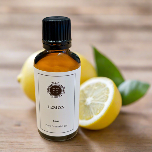 Amber glass essential oil bottle with white label with Under Your Sink logo and description lemon essential oil. Has blurred images of lemon in background