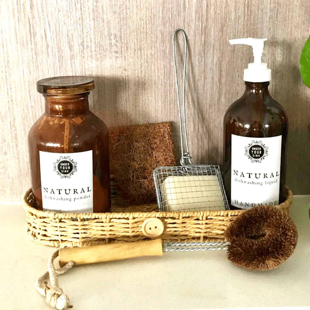 A kitchen top with handmade dish liquid and dish powder in a basket with eco-friendly dish brush for green cleaning